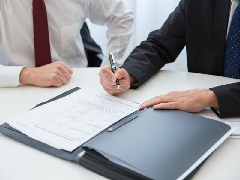 Two professionals reviewing documents and signing papers.